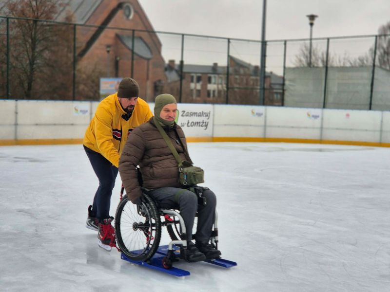 Zdjęcie Kamila Walczyk pchającego Pana Wiesława na wózku na lodowisku